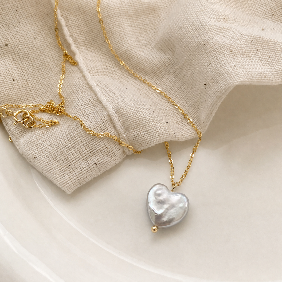 Heart-shaped baroque pearl necklace on white linen